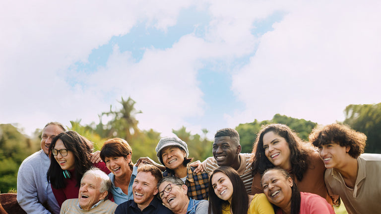 Group of people posing together outdoors with a clear sky and greenery in the background
