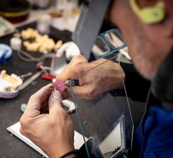 Person working on a small object with tools in a workshop setting