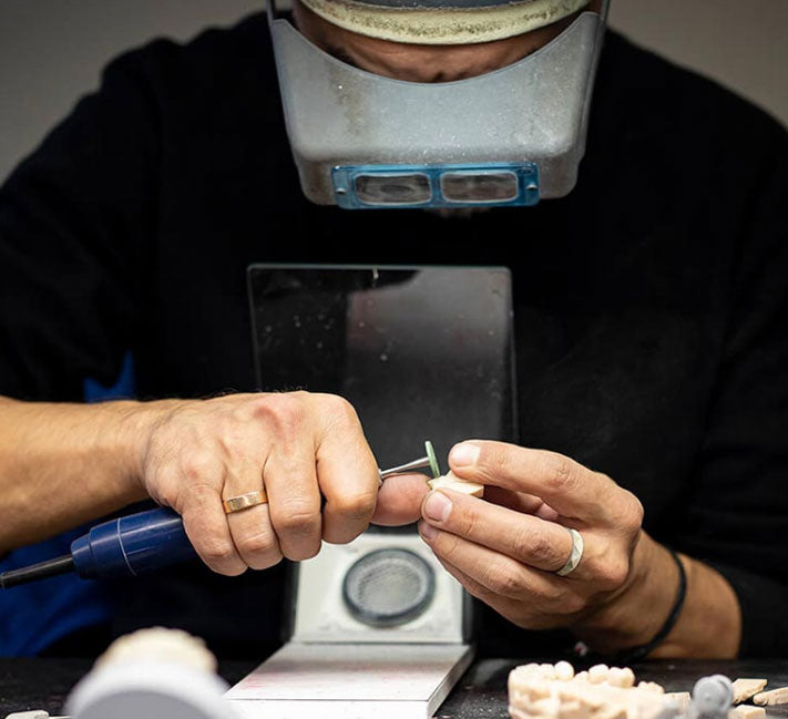 Person working on a small object with a magnifying glass and tools