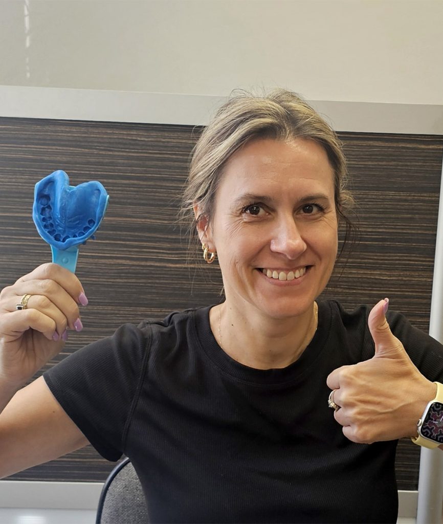Person holding a blue object with a handle, giving a thumbs-up gesture.