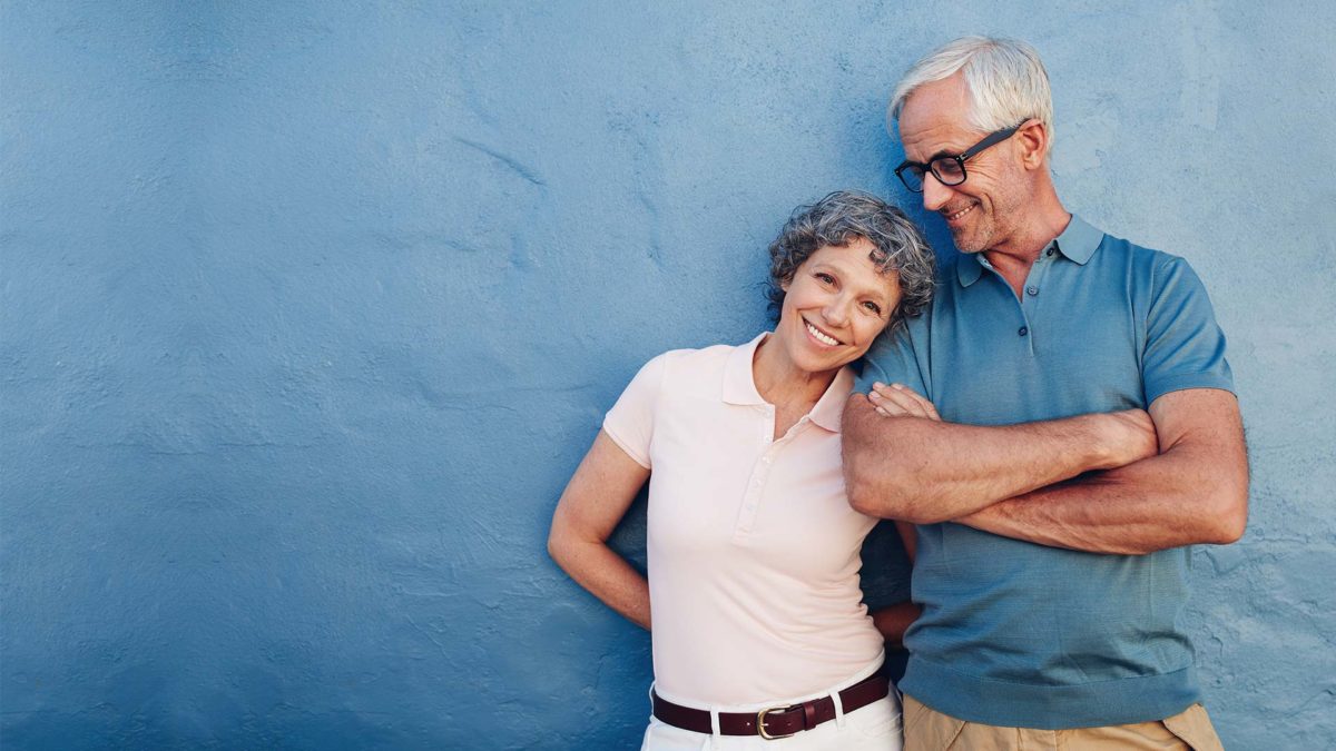 Old couple standing against blue background