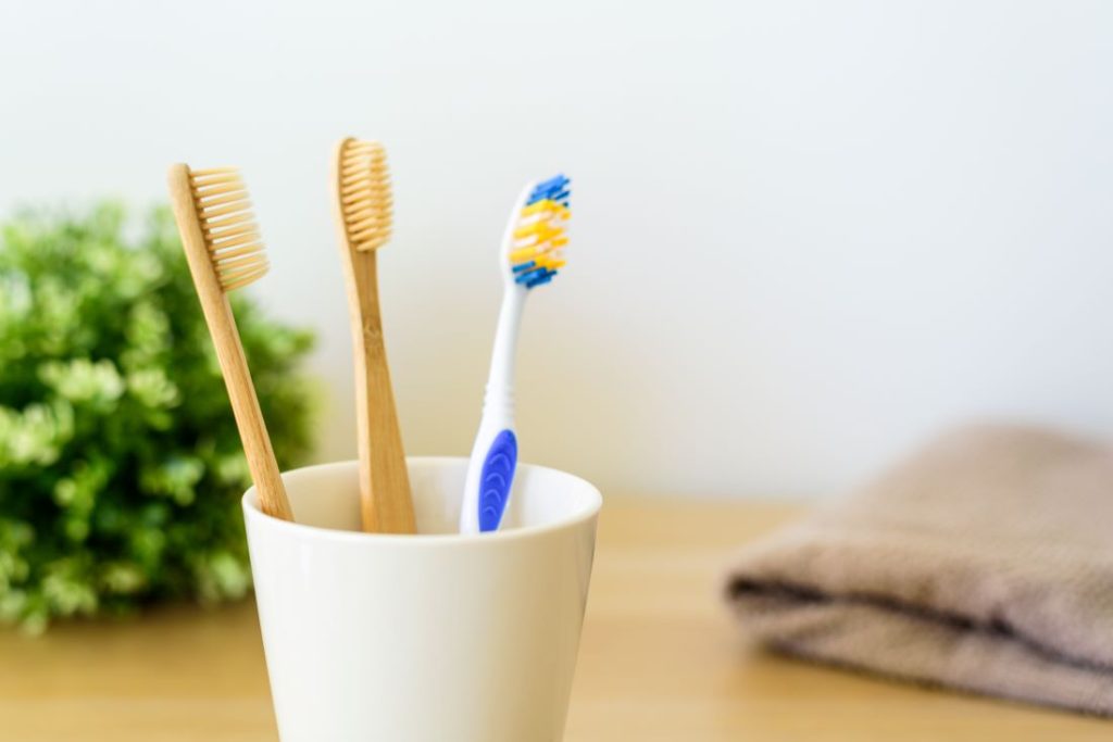 A ceramic cup with three tooth brushes in it