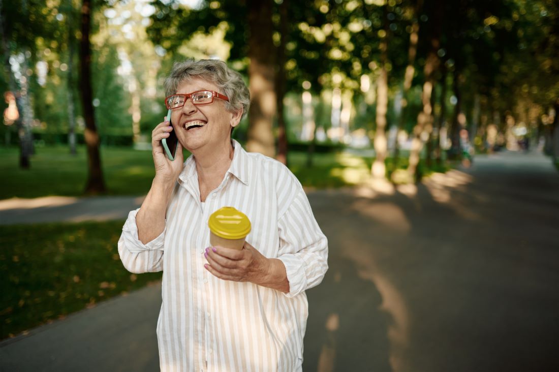 woman wearing glasses using mobile phone in summer park