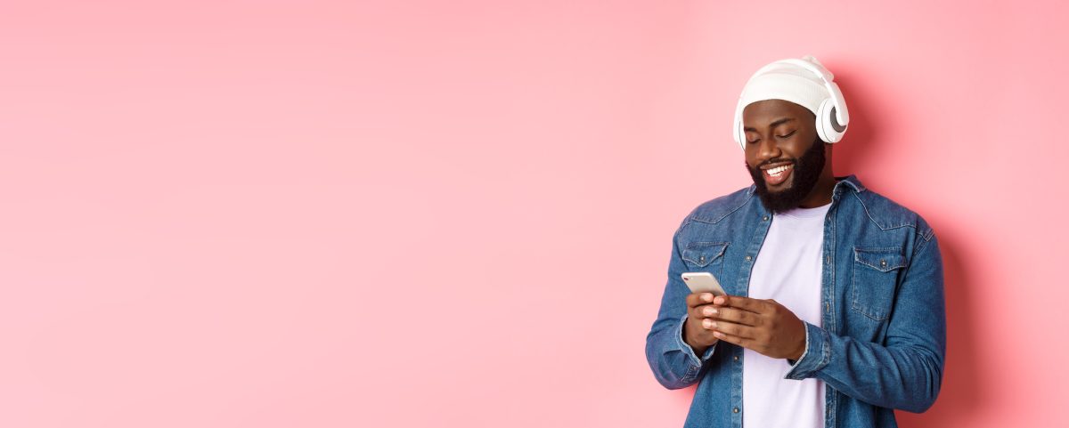 An African American man smiling using his phone