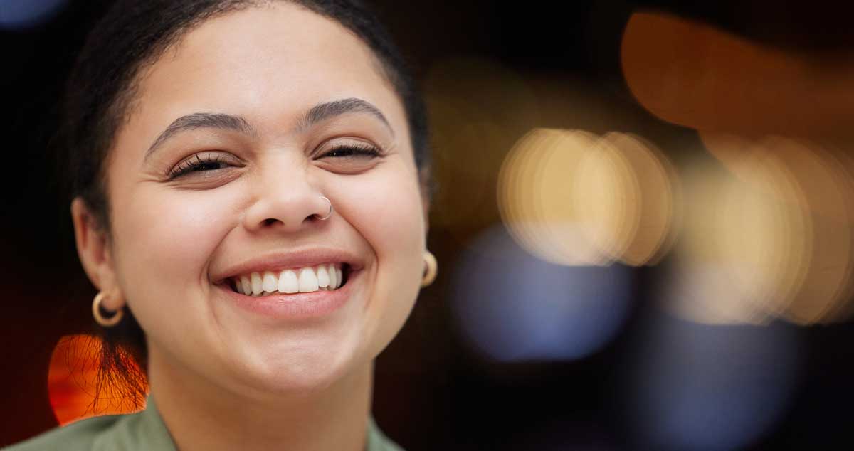 a young woman smiling at the camera in front of a dark background