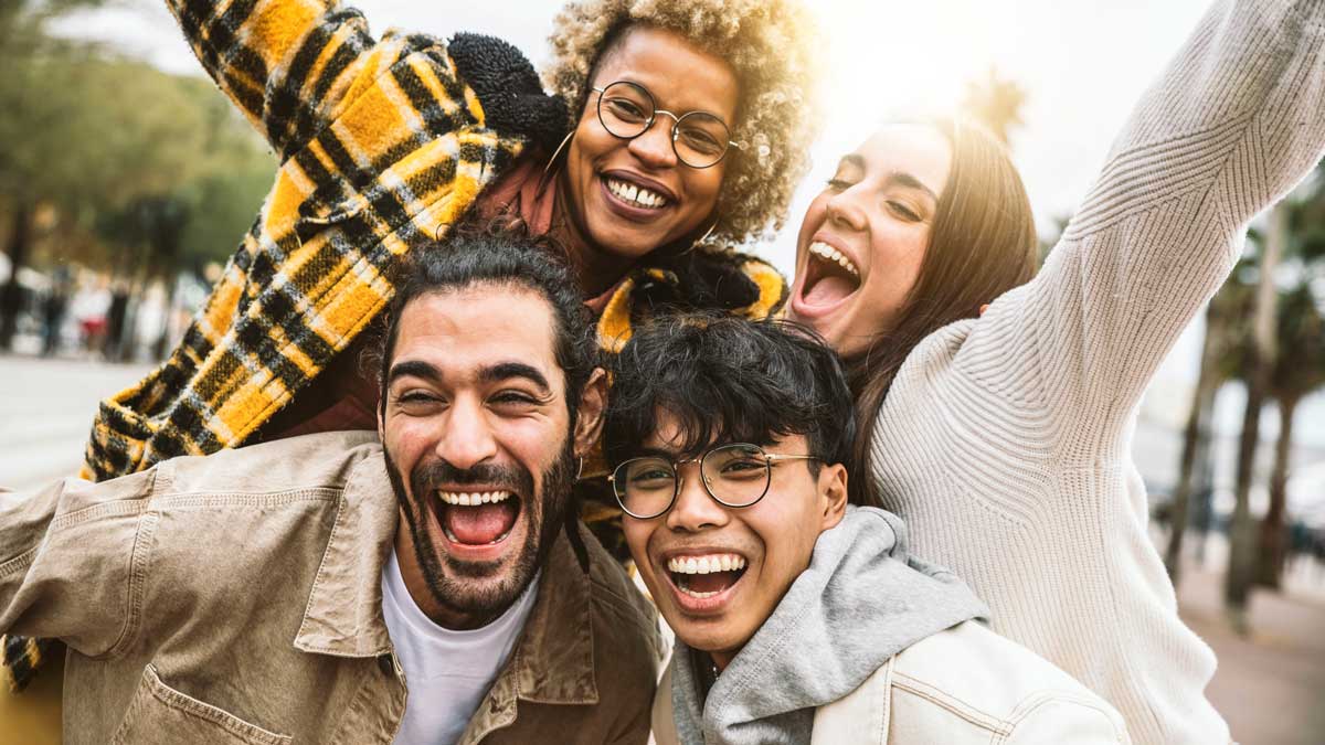 Diverse group of young friends laughing and smiling outdoors during a fun day out