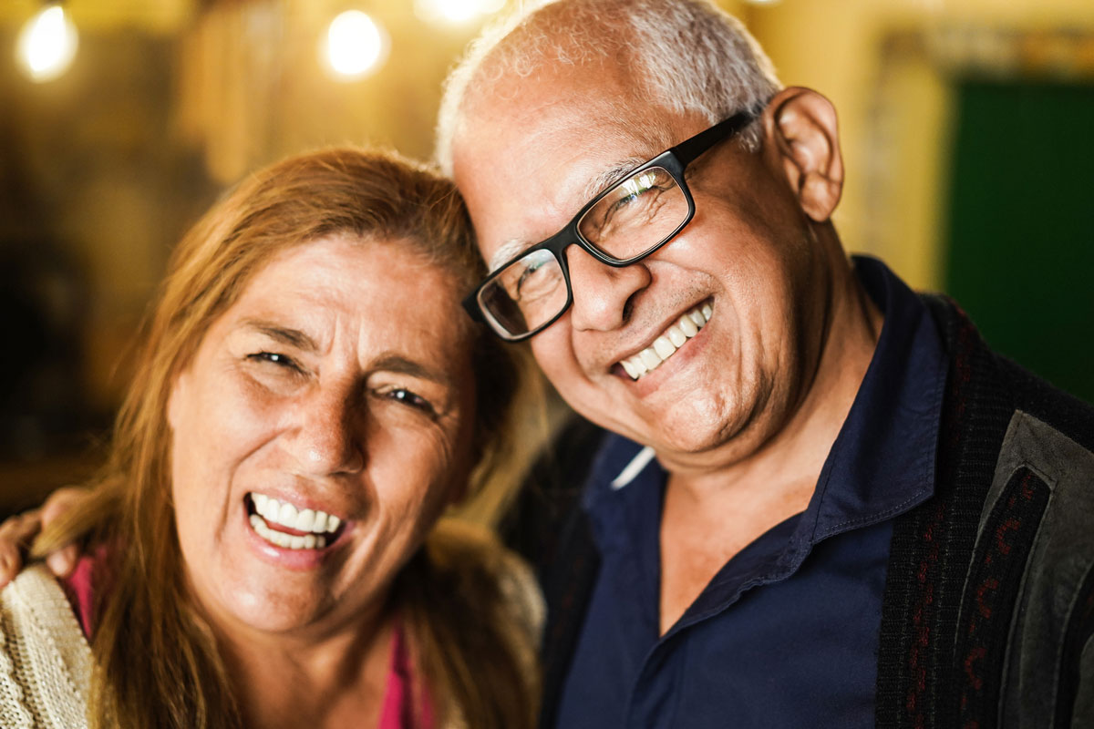 Smiling older couple laughing, with beautiful lights in the background, enjoying a joyful moment together
