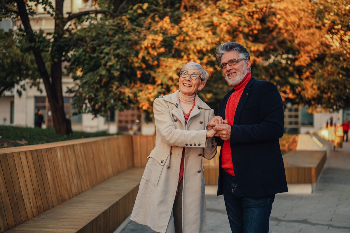 Smiling senior couple holding hands and enjoying a walk together in a park during autumn